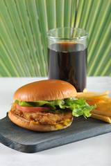 round hamburger with chicken cutlet and French fries and a glass of coke
