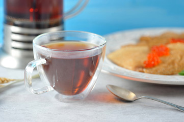 mug with tea and pancakes in a plate with caviar