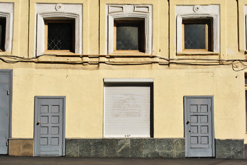 Obraz na płótnie Canvas Painted in yellow wall of building with boarded up windows and closed doors