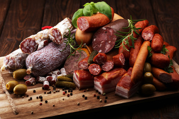 Food tray with delicious salami, ham,  fresh sausages, cucumber and herbs. Meat platter