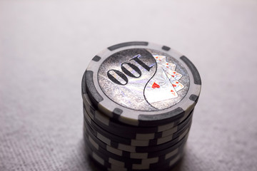 A stack of black, gray game chips with a denomination hundred on a dark background.  Passion, game, poker, casino.