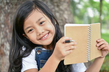 Fototapeta premium Education Concepts. The girl is reading a book in the garden. Beautiful girl is seriously studying. Beautiful girls are happy learning.