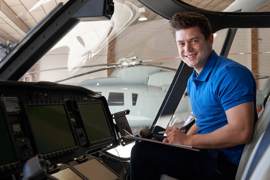 Portrait Of Male Aero Engineer With Clipboard Working In Helicopter Cockpit