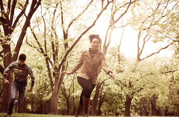 Happy African American couple running trough park.