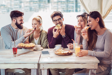 Young friends sharing pizza in a indoor cafe