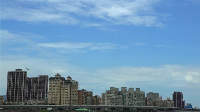 4k View of military plane flying low over the buildings in Taipei city. Airplane fly above skyscrapers. Plane in the air up houses an urban area in Taiwan. Flight trip with blue sky-Dan