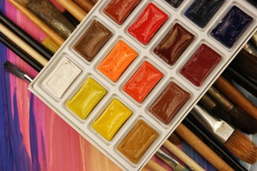 Sets of watercolor paints and various brushes on the background of sketches