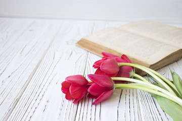 old book and tulips on white wooden table