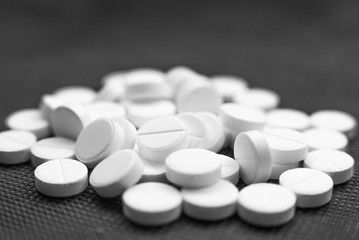 White pills on black background closeup
