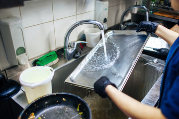 cook washes the tray with running water