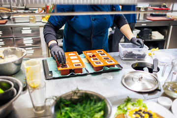 cook puts pieces of chocolate on desserts