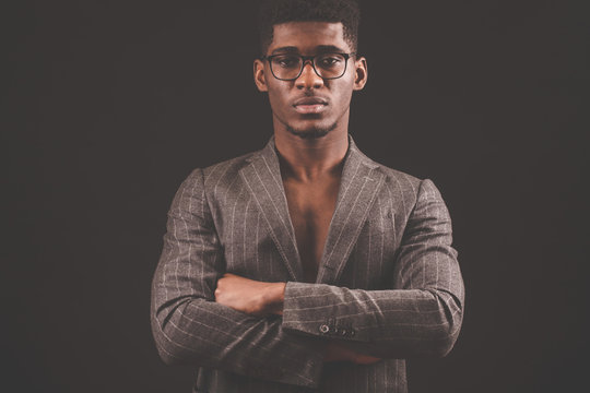 Portrait of successful serious Afro man in glasses with crossed arms isolated on the black background. confident leader