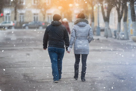 Couple in love on a walk in the city square in the snow