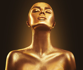 Fashion art golden skin woman portrait closeup. Gold, jewelry, accessories. Model girl with golden glamour shiny makeup
