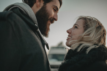 Close up portrait of blonde woman and bearded man looking to each other at the eyes in love.