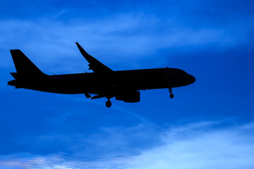 Silhouette passenger airplane flying away in to sky high altitude on sunset