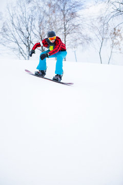 Picture of athlete in helmet with snowboard riding in snowy resort