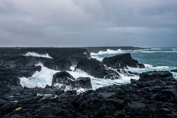 Rugged Icelandic coastline with big  waves hitting the black rocks at overcast evening in south west Iceland.