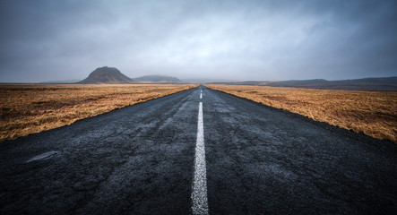 A road leading to distance at cloudy day with mountains in the background