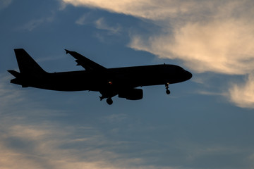 Fototapeta na wymiar Silhouette passenger airplane flying away in to sky high altitude on sunset