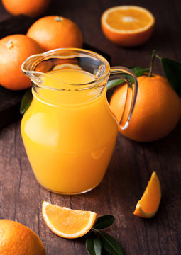 Glass jar of raw organic fresh orange juice on wood