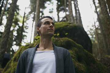 Young stylish man sitting on the precipice of the river on the phone