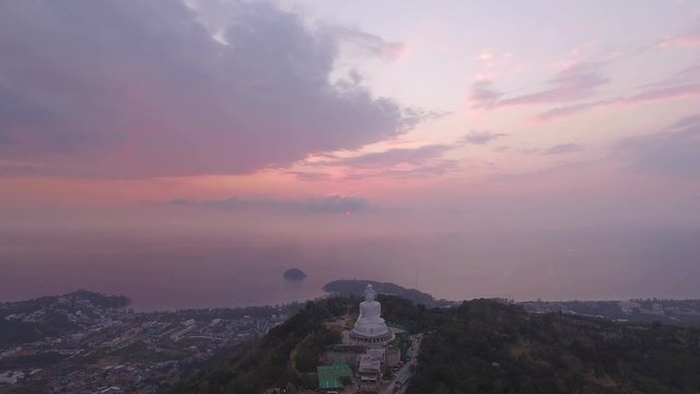 aerial view the white big Buddha statue on the high mountain in sunset time. Phuket big Buddha on hilltop can see around Phuket island behind Phuket big Buddha is Karon gulf in front is Chalong gulf.