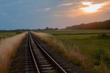 Fototapeta na wymiar einsames Gleis, die strecke verläuft im Sonnenuntergang 