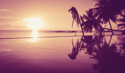 Fantasy sunset with silhouettes of palm trees reflecting on infinite pool and calm sea on the background in the island of Ko Pha Ngan, Thailand. Paradise, exotic landscape, perfect getaway concept
