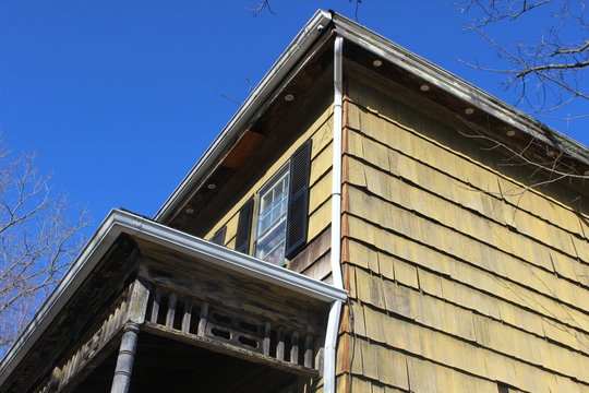 Historic New England house in disrepair with faded and chipped paint 