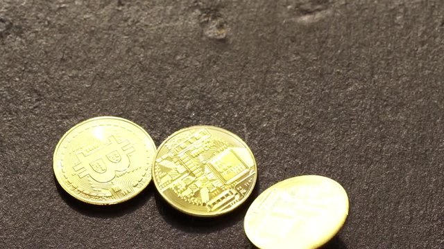 Coins golden bitcoin fall and twist on the graphite surface. Slow motion video. 120 fps.