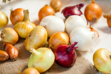 assorted fresh onions on a wooden table. wallpaper for grocery shopping and cooking food concept