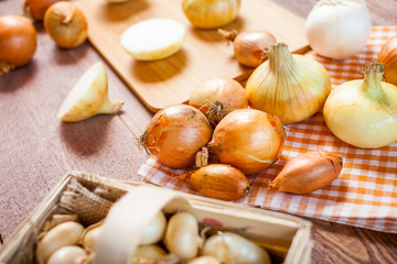 assorted fresh onions on a wooden table. wallpaper for grocery shopping and cooking food concept