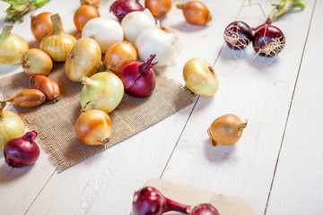 assorted fresh onions on a wooden table. wallpaper for grocery shopping and cooking food concept