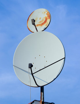 A large and a small parabolic satellite communications antennas against a blue sky  