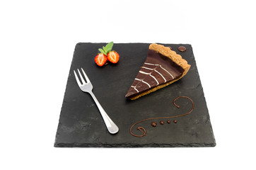 Chocolate tart with silver fork on black plate