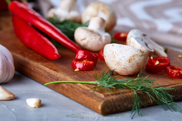 Vegetables on cutting board, plate with salt over white textured background, close-up, selective focus.