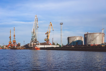 Fototapeta premium Port of a large Russian city with ships and various equipment on the background of the river.