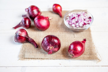 bulbs of fresh onion and bowl with chopped onion on a wooden table background. food cooking concept