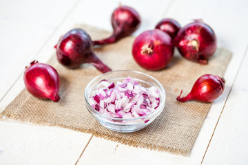 bulbs of fresh onion and bowl with chopped onion on a wooden table background. food cooking concept
