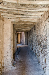 Fototapeta premium Ancient footpath tunnel through clay buildings in Oman