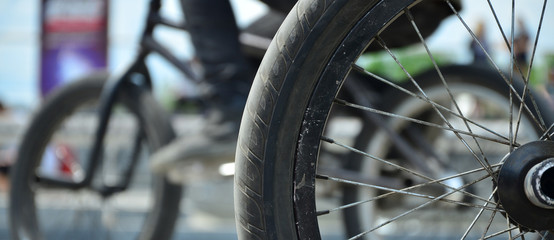 A BMX bike wheel against the backdrop of a blurred street with cycling riders. Extreme Sports...
