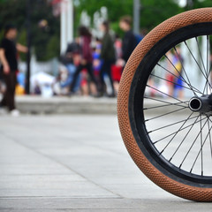 A BMX bike wheel against the backdrop of a blurred street with cycling riders. Extreme Sports...