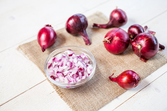 bulbs of fresh onion and bowl with chopped onion on a wooden table background. food cooking concept