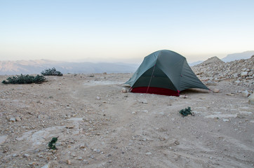 Wild camping in Oman with tiny tent on rocky underground in Oman mountains