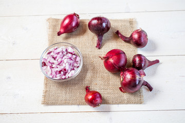 bulbs of fresh onion and bowl with chopped onion on a wooden table background. food cooking concept