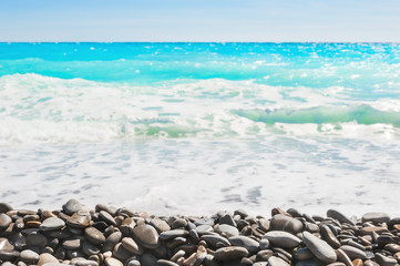 Fototapeta na wymiar Pebbles on the beach, blurred sea in the background