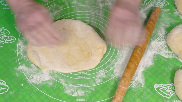 Close-up, Hands of an Elderly Woman with the help of a Wooden Roller Rolling A Piece of Test on the Table