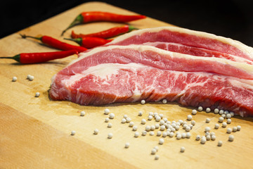 Raw bristket on a wooden board with white pepper
