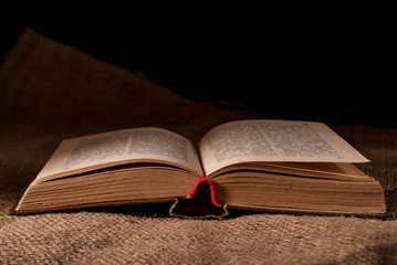 unfolded book on the surface with burlap and pine cone and a cup